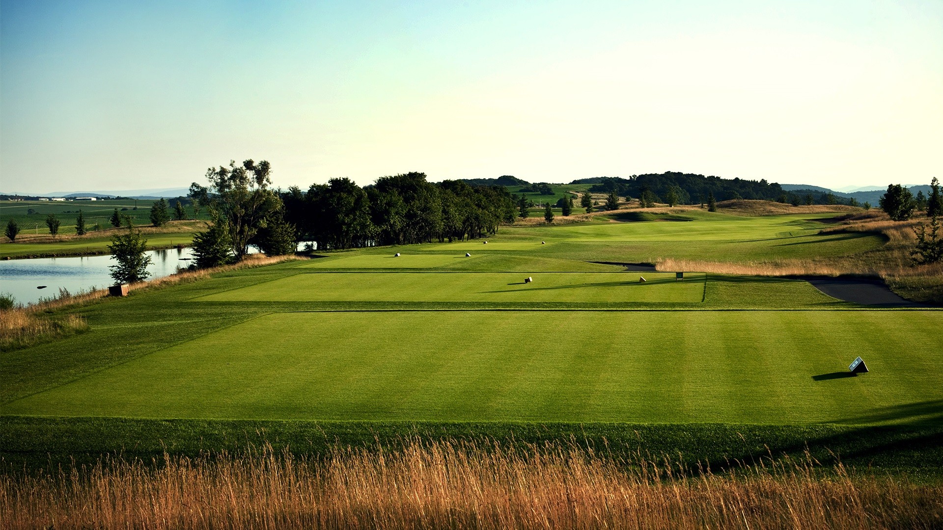 Solbelyst golfbana med vatten och träd på Albatross Golf Resort nära Prag