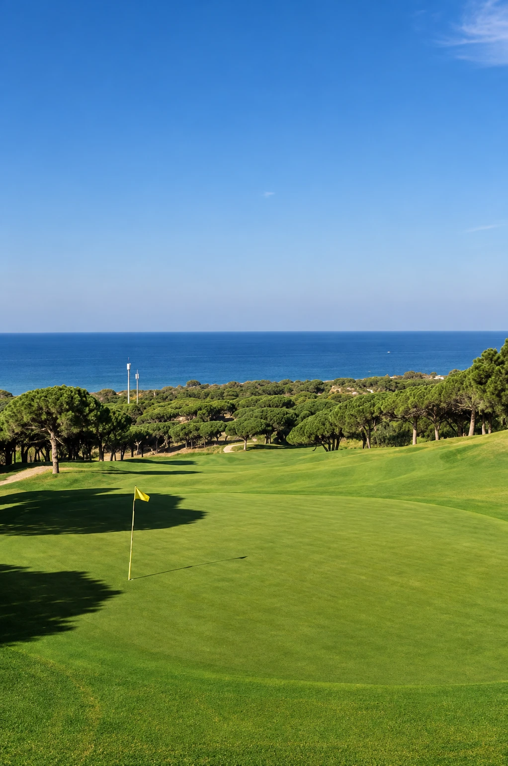 Green med flagga på Cabopino Golf, med träd och Medelhavet i bakgrunden