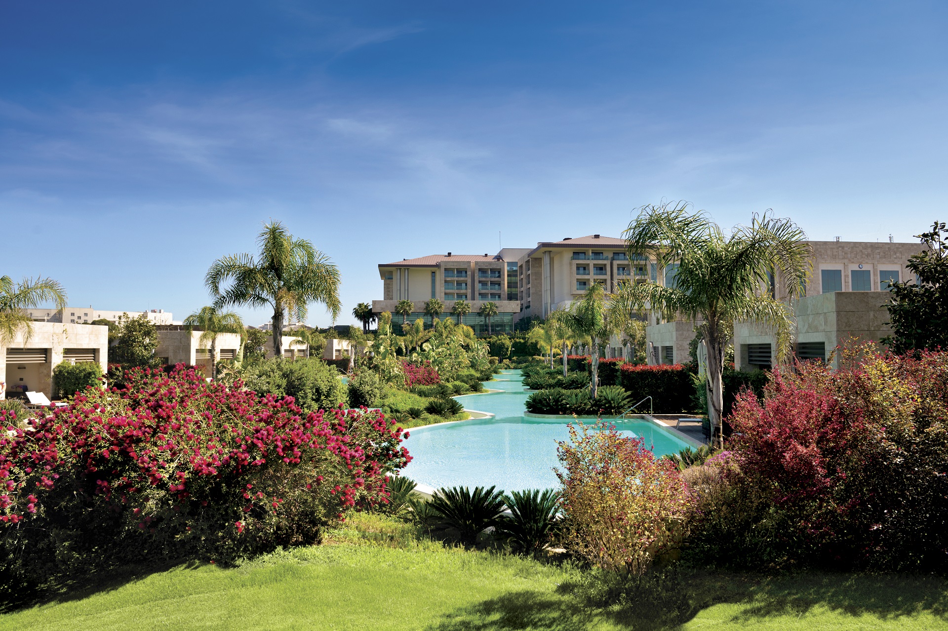 Regnum Carya i Belek med palmer, blommor och pool framför hotellet